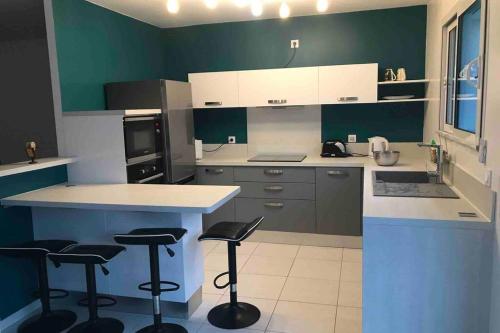 une cuisine avec des placards verts et blancs et des tabourets de bar dans l'établissement Maison lumineuse 3 chambres bordeaux sud, à Pont-de-la-Maye