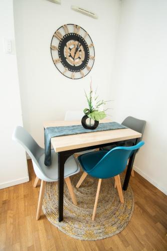 une table à manger avec deux chaises et une horloge murale dans l'établissement Appartement chic avec parking gratuit à Paris, à Gentilly