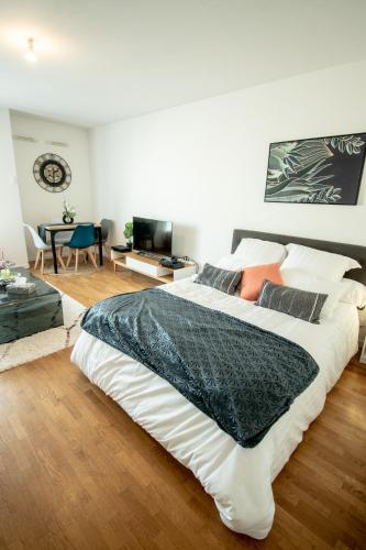 Cette chambre comprend un grand lit blanc et une table. dans l'établissement Appartement chic avec parking gratuit à Paris, à Gentilly