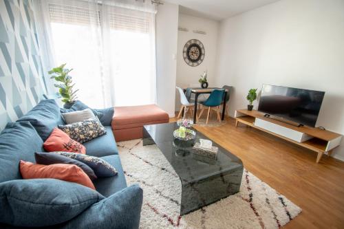 a living room with a blue couch and a television at Appartement chic avec parking gratuit à Paris in Gentilly