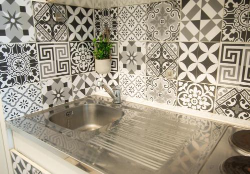 a kitchen with a sink and tiles on the wall at Appartement chic avec parking gratuit à Paris in Gentilly