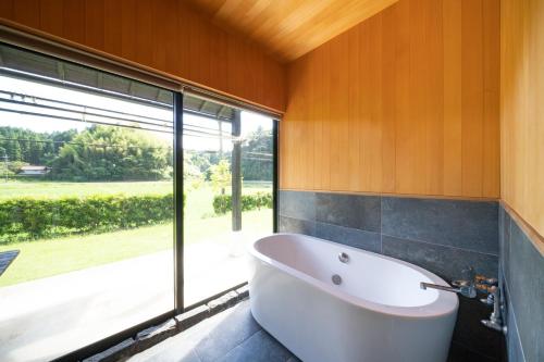 a bath tub in a bathroom with a large window at Isumi Enokisawa -いすみ 四季の家 榎澤- ペット可 in Isumi