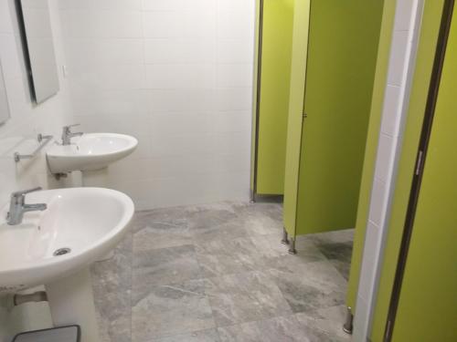 baño con 2 lavabos y puerta verde en Albergue La Plaza, en Tineo
