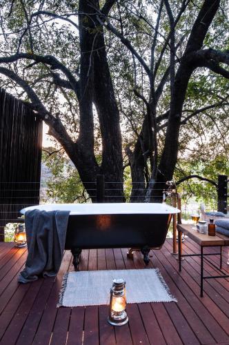 a bath tub sitting on a deck next to a tree at Jock Safari Lodge in Skukuza