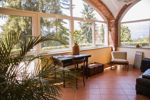 Habitación con ventanas, mesa y planta en La Foresteria di Villa Piazzo en Pettinengo