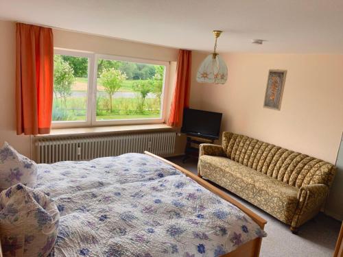 a bedroom with a bed and a couch and a window at FeWo25-Zimmer-am-Bodensee in Markdorf