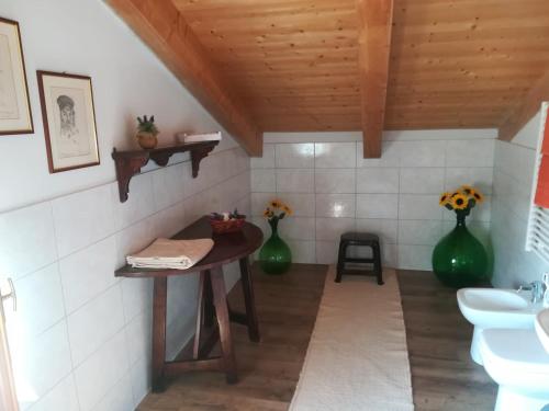 baño con mesa y 2 jarrones verdes en Alloggio Alla Collina, en Arcugnano