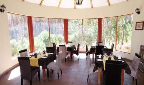 a dining room with tables and chairs and large windows at Hotel El Refugio in Chivay