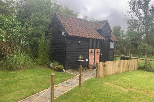 a black house with a fence in a yard at Windsor/Ascot/Bracknell beautiful barn in Bracknell