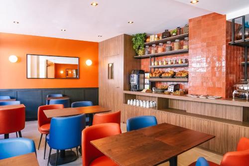 a restaurant with wooden tables and blue chairs at Timhotel Le Louvre in Paris