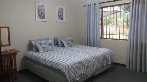 a bedroom with a bed with blue and white sheets and a window at 6 Fish Eagles in St Lucia