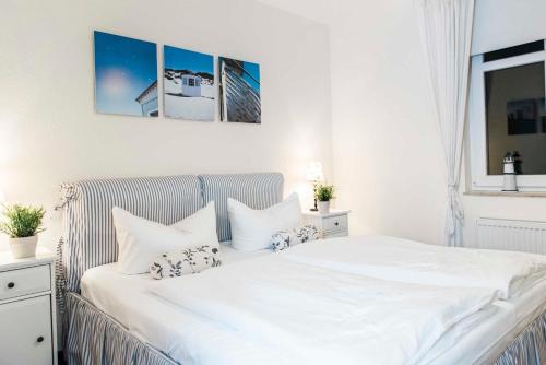 een slaapkamer met een wit bed met witte lakens en kussens bij Residenz Prorer Wiek App 10 strandnah, mit Balkon by Unsere Urlaubszeit in Binz