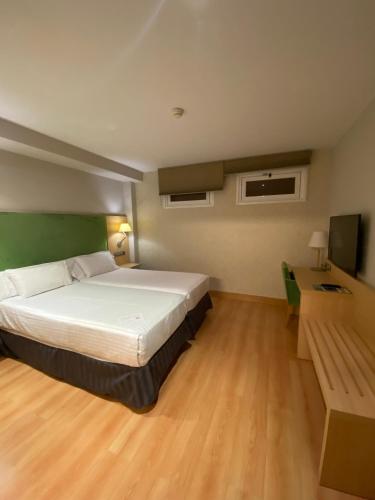 a bedroom with a bed and a desk and a television at U Hotel Villa-Gomá in Zaragoza