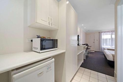 a white kitchen with a microwave on a counter at Comfort Inn Glenfield in Toowoomba