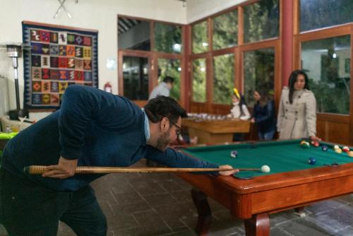 a man playing pool with a cue on a pool table at Hotel El Refugio in Chivay