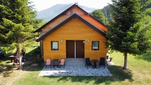 a small house with a porch and chairs in front of it at Apartmani Šarović in Tjentište
