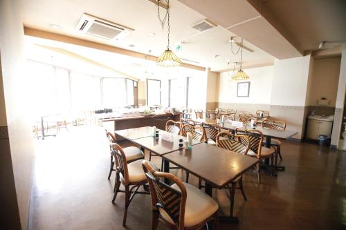a dining room with tables and chairs and windows at Kuretake Inn Gotemba Inter Gold Cabin in Gotemba