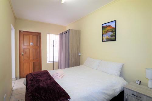 1 dormitorio con cama blanca y puerta de madera en Garden Cottage in Edenvale, en Edenvale