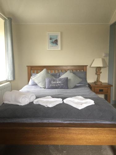Una cama con dos toallas encima. en The Wheel House, en Mevagissey