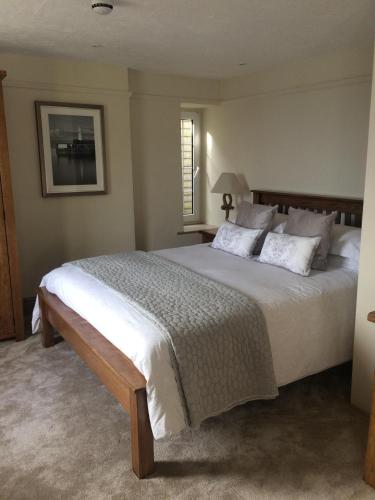 een slaapkamer met een groot bed met witte lakens en kussens bij The Wheel House in Mevagissey