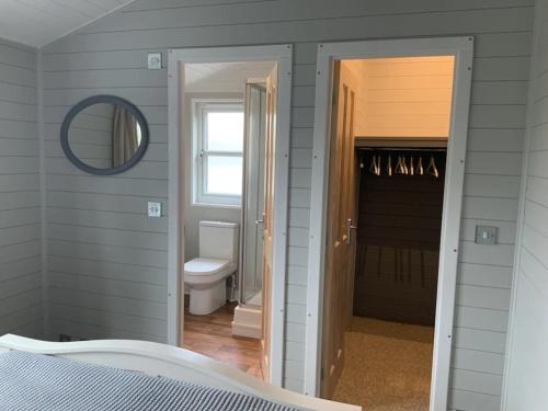 um quarto com uma porta que leva a uma casa de banho em Holly Blue - Cosy wooden lodge Kippford em Dalbeattie