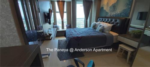 a bedroom with a bed and a desk and windows at The Paneya@Anderson Apartment in Surabaya