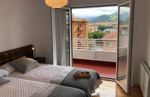 ゲルニカ・イ・ルノにあるPiso céntrico y tranquilo en Gernikaのベッドルーム1室(ベッド1台付)、景色を望むバルコニーが備わります。