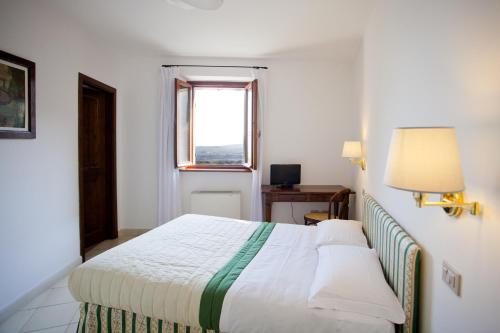 a bedroom with a white bed with a window at Casa Oliva borgo del Benessere Olistico in Bargni