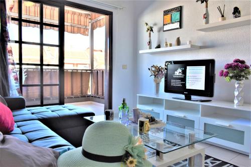 a living room with a blue couch and a tv at Cozy Apartment Tenerife South Wifi & Pool in Costa Del Silencio