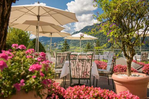 a patio with tables and chairs with flowers and umbrellas at Alpines Lifestyle Hotel Tannenhof in Sankt Johann im Pongau