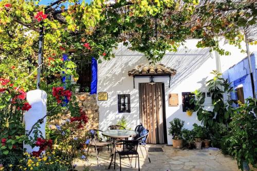 a patio in front of a white house with flowers at La Posada Amena in Carcabuey