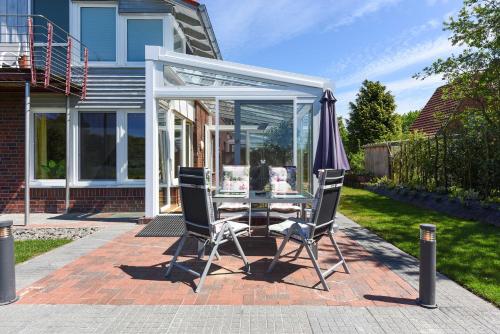 a patio with an umbrella and a table and chairs at Ferienwohnungen im Haus Nordlichter in Holtgast