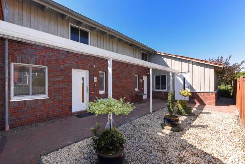 a brick building with a courtyard with potted plants at Ferienwohnungen im Haus Nordlichter in Holtgast