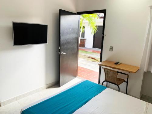 um quarto com uma cama, uma televisão e uma secretária em Don David Sabana Hotel em Sabana de Torres