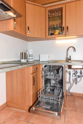 an open dishwasher in a kitchen with a sink at Ferienwohnungen im Haus Nordlichter in Holtgast