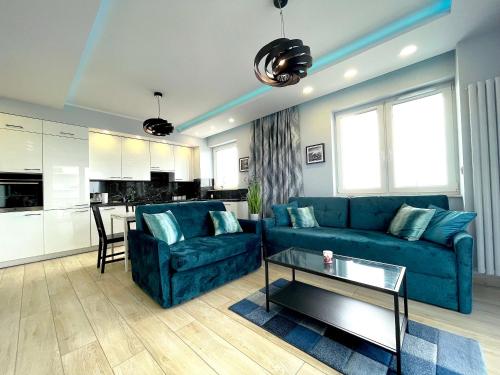 a living room with a blue couch and a kitchen at Apartament z tarasem i widokiem na Odrę in Wrocław