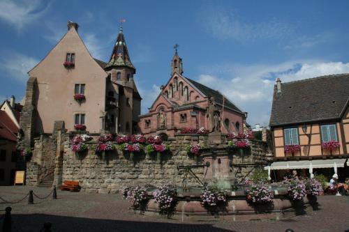a group of buildings with flowers on a stone wall at Résidence Vénus in Eguisheim