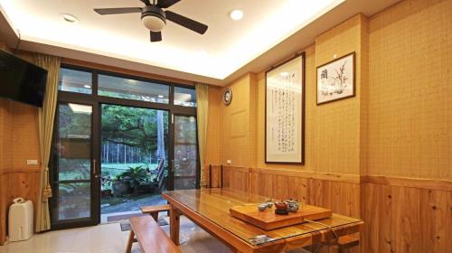 a dining room with a wooden table and a ceiling fan at Qian's Garden Inn in Lugu Lake