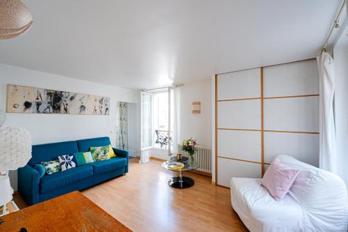 salon z niebieską kanapą i stołem w obiekcie Bright and lovely parisian apartment w Paryżu