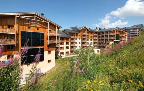a group of apartment buildings on a hill with flowers at Résidence Odalys Front de Neige in Plagne Villages