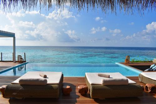 a swimming pool with two beds and the ocean at Baglioni Resort Maldives - Luxury All Inclusive in Dhaalu Atoll