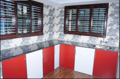 a kitchen with red and white cabinets and windows at Coorg Residency home stay in Kushālnagar