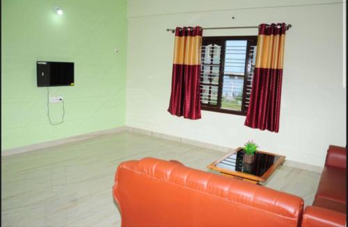 a living room with a leather couch and a window at Coorg Residency home stay in Kushālnagar