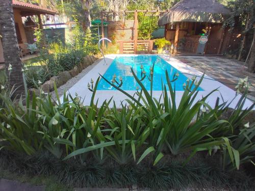 a swimming pool with plants in front of a house at Pousada da Terra Paraty in Paraty