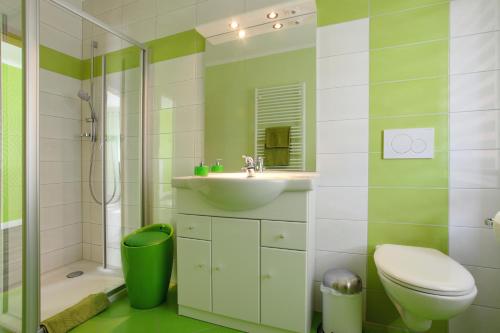 a green and white bathroom with a toilet and a sink at Restaurant & Pension Rüssel - Pub in Sangerhausen