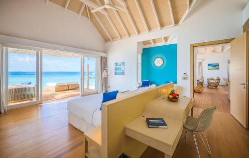 a bedroom with a bed and a desk with a view of the ocean at Baglioni Resort Maldives - Luxury All Inclusive in Dhaalu Atoll