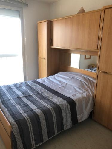 a bedroom with a large bed and wooden cabinets at Belle vue sur la mer et les Pyrénées in Le Barcarès