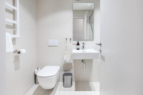 a white bathroom with a toilet and a sink at Tech Spa Coliving&Coworking Spaces in Druskininkai
