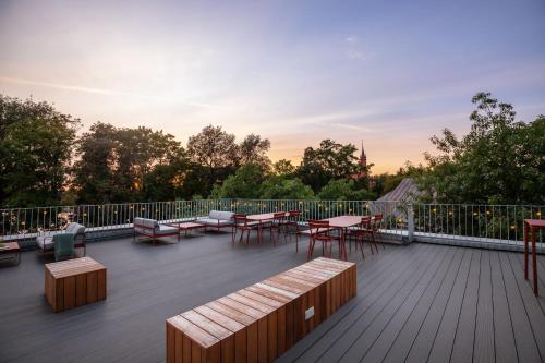a rooftop deck with tables and chairs and the sunset at Tech Spa Coliving&Coworking Spaces in Druskininkai