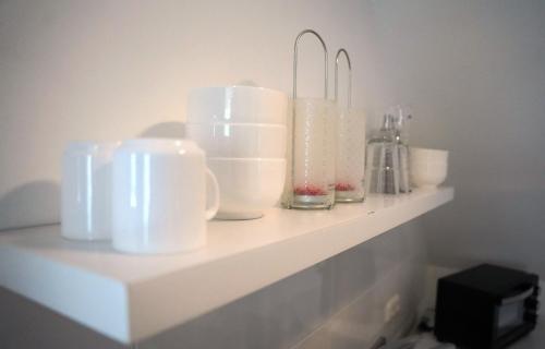 a shelf with white cups and glasses on it at Altstadt Fereienwohnung Hameln in Hameln